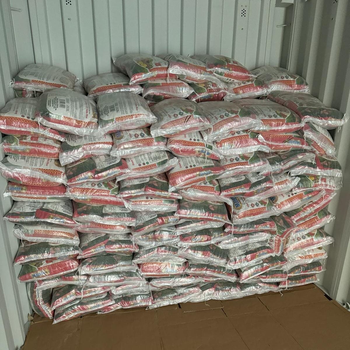A neat wall of shrink-wrapped rice bags filling a shipping container.